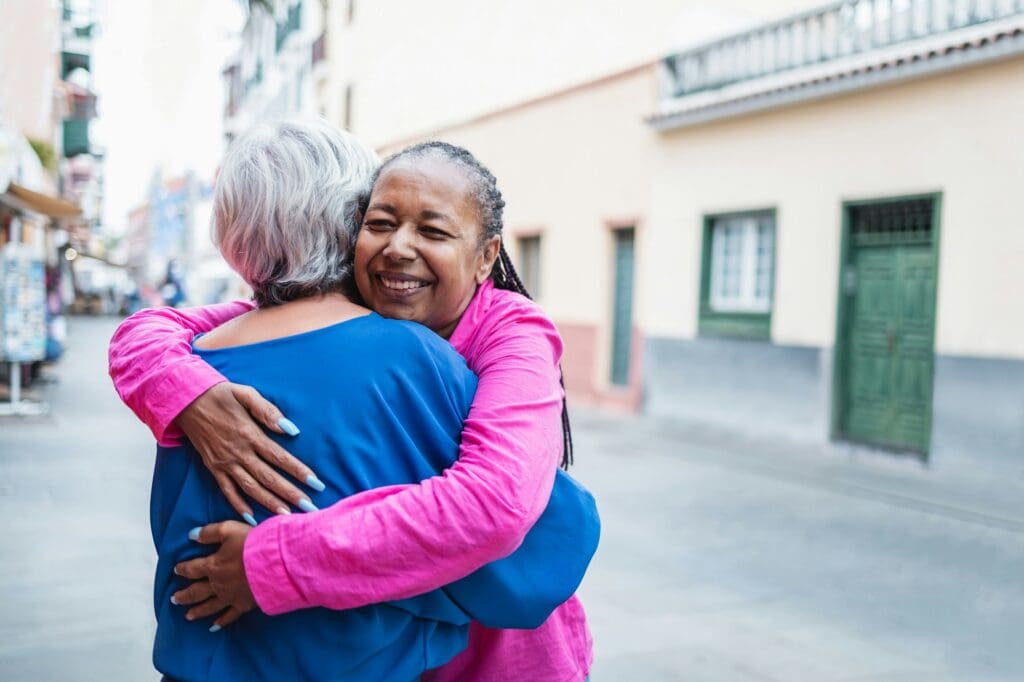 Multiracial senior women hugging each other - Diverse elderly friendship community